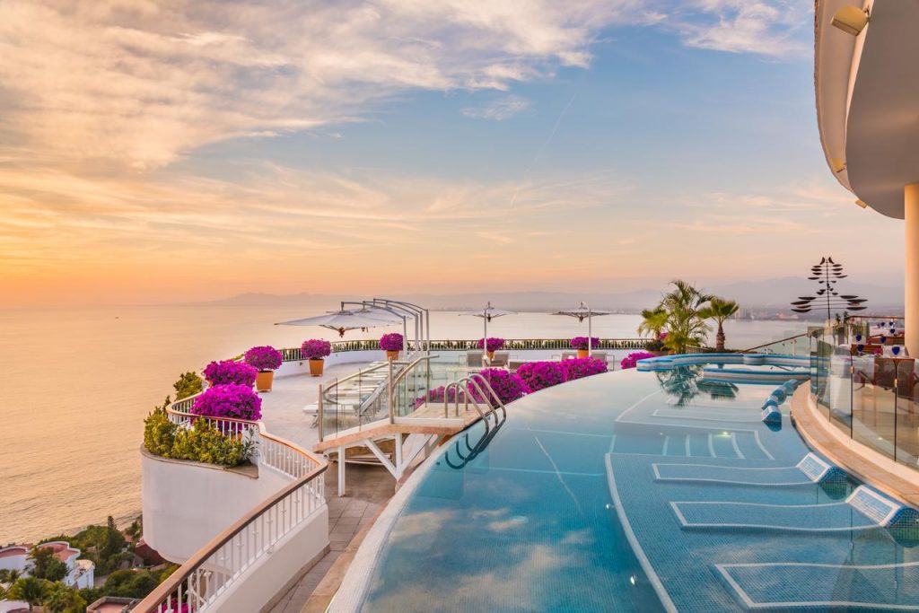 view of inifinity pool at grand miramar hotel looking over the ocean at sunset