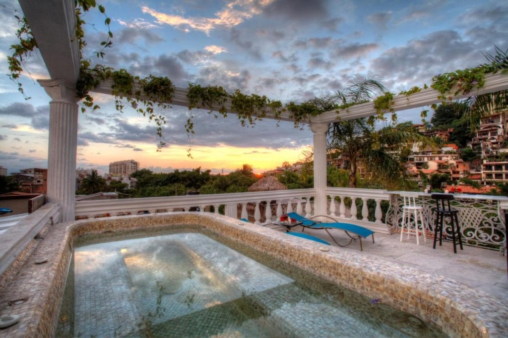 Tranquil rooftop pool at Hotel Boutique Rivera Del Rio, surrounded by lush greenery and overlooking Puerto Vallarta's charming river, providing a serene escape for guests to unwind and enjoy the tropical sun.