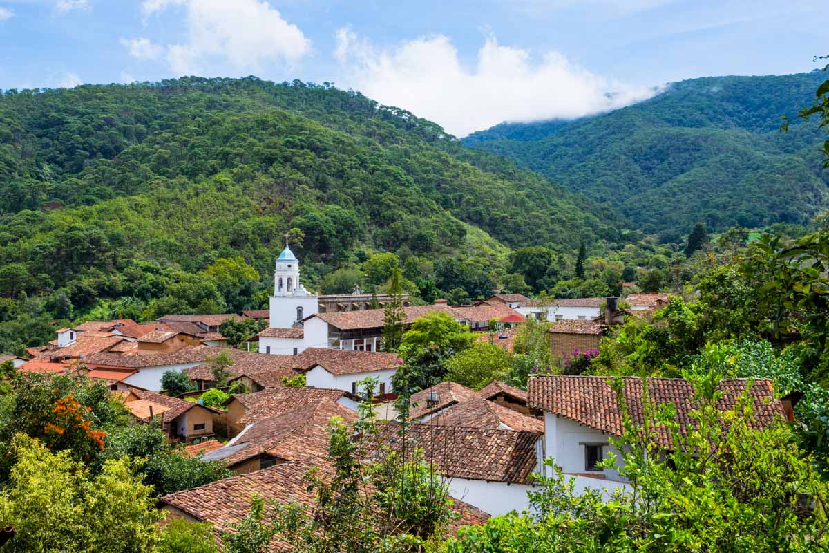 Charming town nestled in a lush green valley with traditional buildings and a church steeple rising above the rooftops, perfect for day trips from Puerto Vallarta.