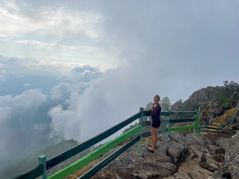 lora standing next to viewpoint above the clouds