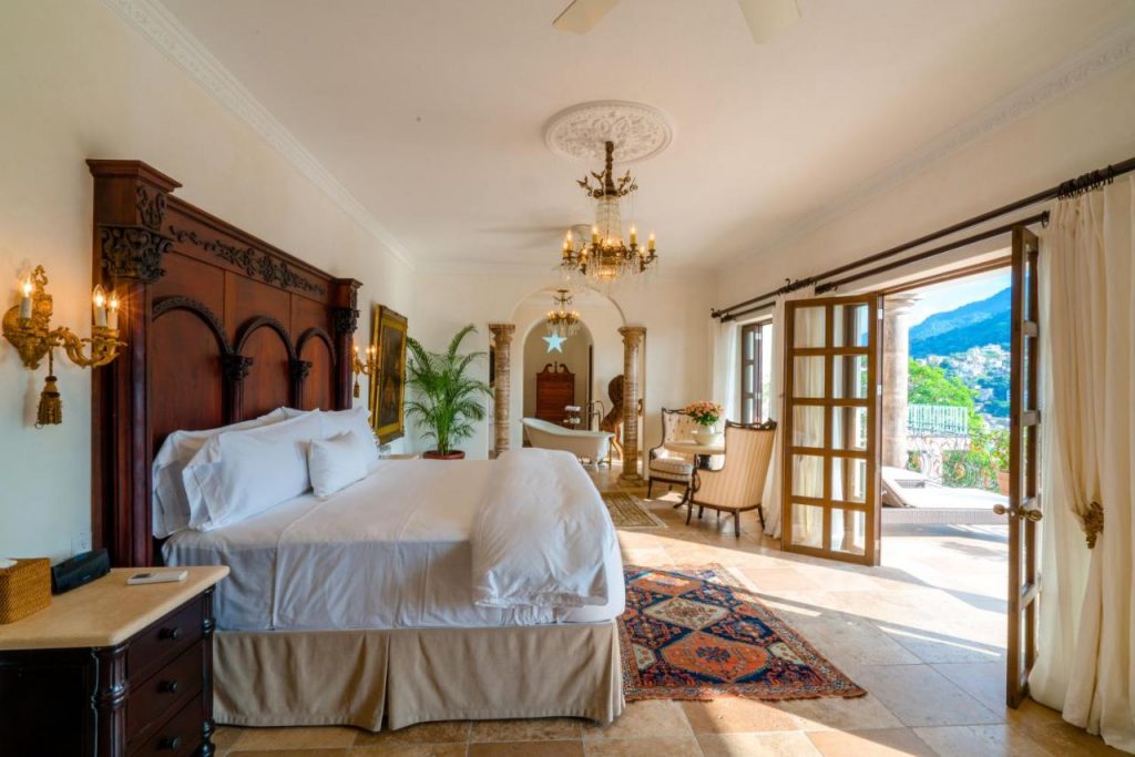 Romantic suite interior at Casa Kimberly, featuring a luxurious canopy bed, ornate furnishings, and open French doors leading to a private terrace