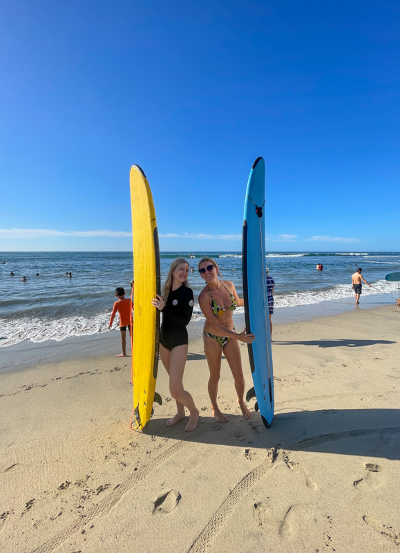 two girls standing with surf boards on beach in sayulita