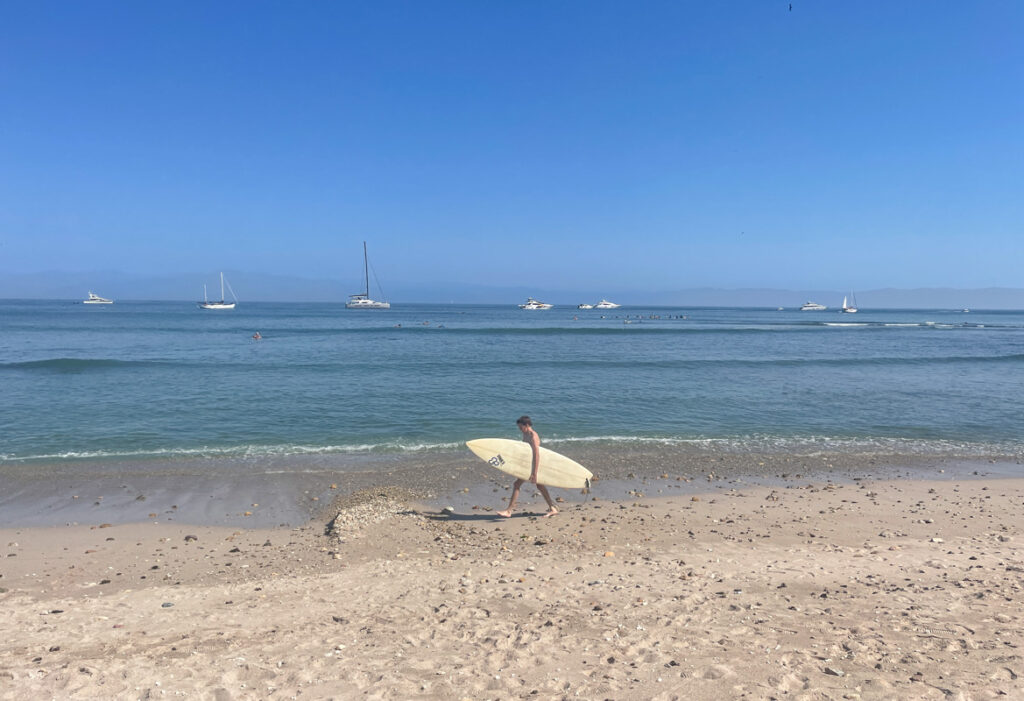 surfer waling with board along beach in punta pita while surfing near puerto vallara