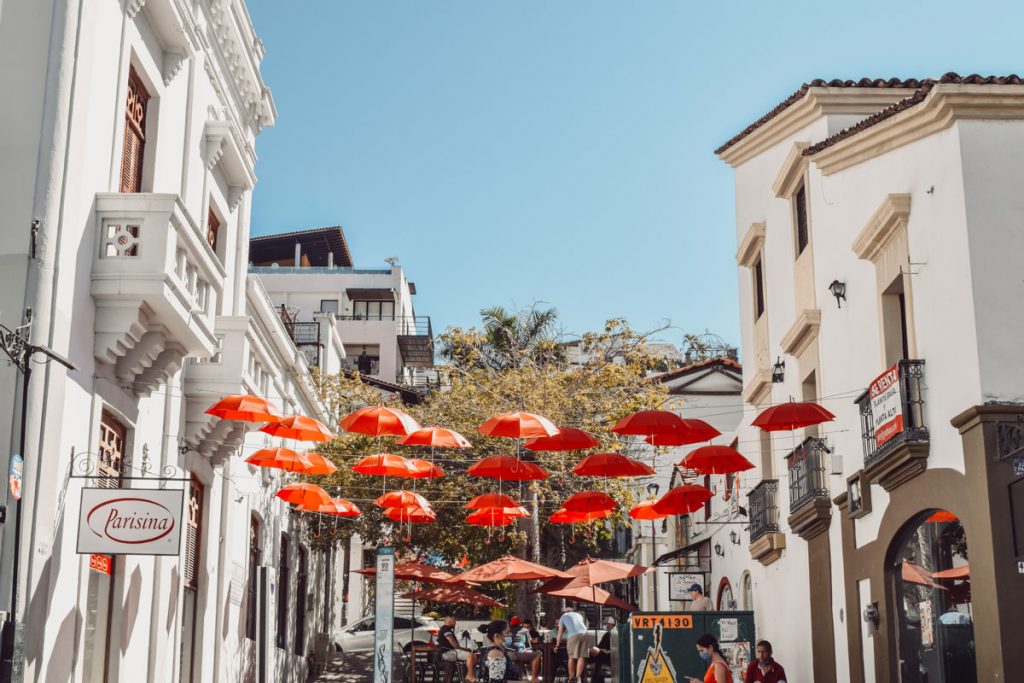 A vibrant street in Puerto Vallarta is adorned with a kaleidoscope of red umbrellas,