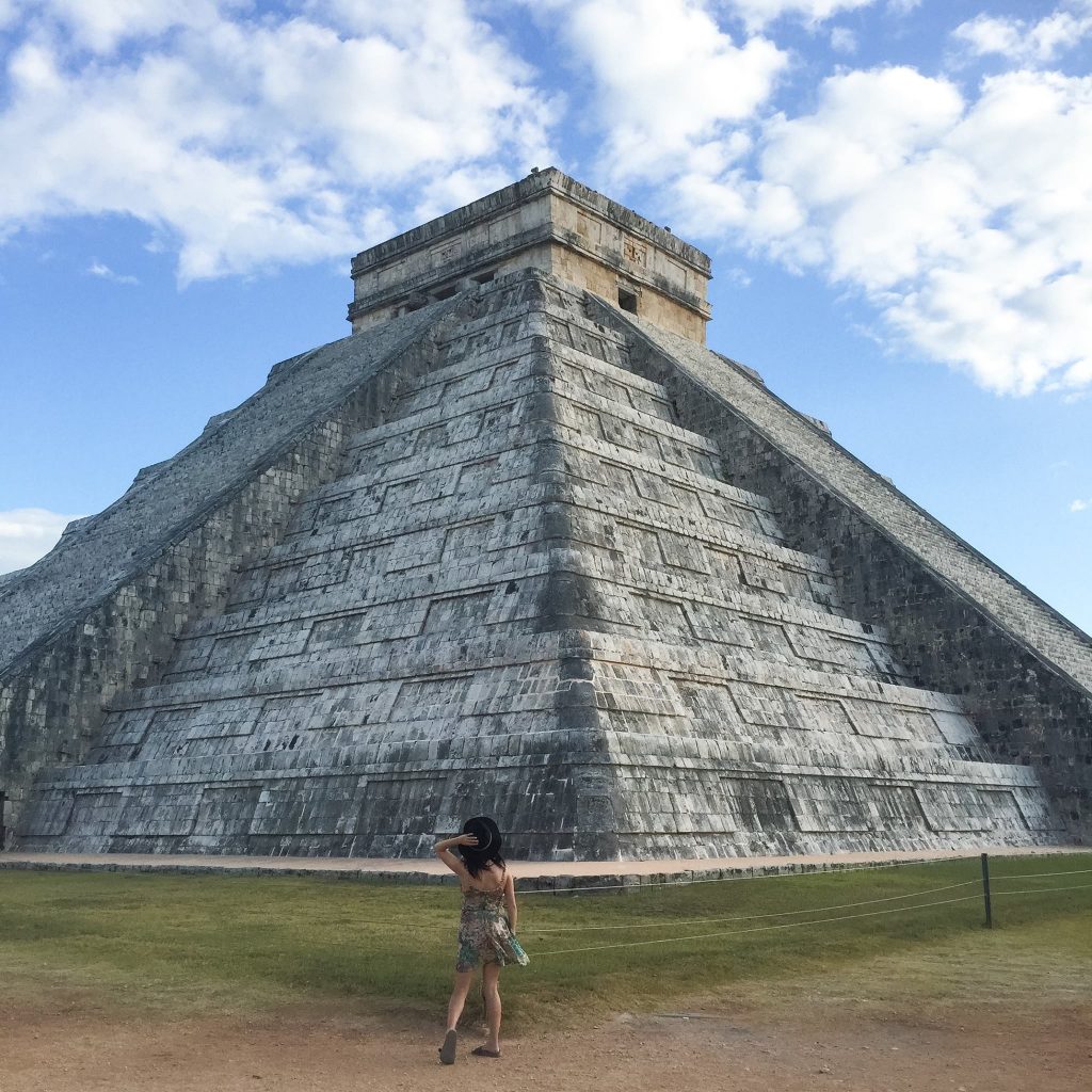 lora staring looking up at chichen itza pyramid in mexico