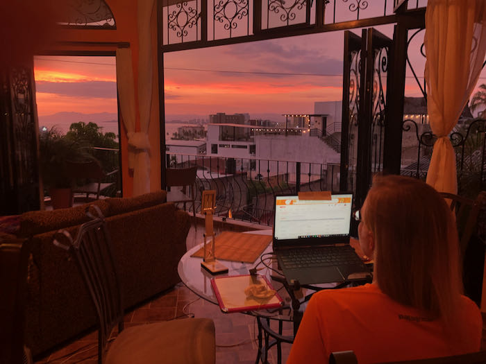 A digital nomad working on a laptop during sunset, exemplifying the freedom and flexibility of remote work in Puerto Vallarta.