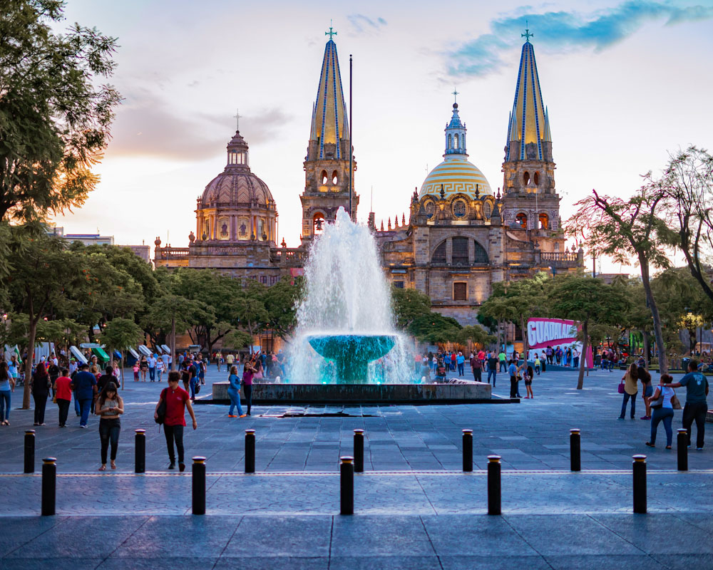 mage of a beautiful church and square in Guadalajara, Mexico, with the magnificent architecture of the church complemented by a bustling square filled with people, colorful buildings, and a vibrant atmosphere