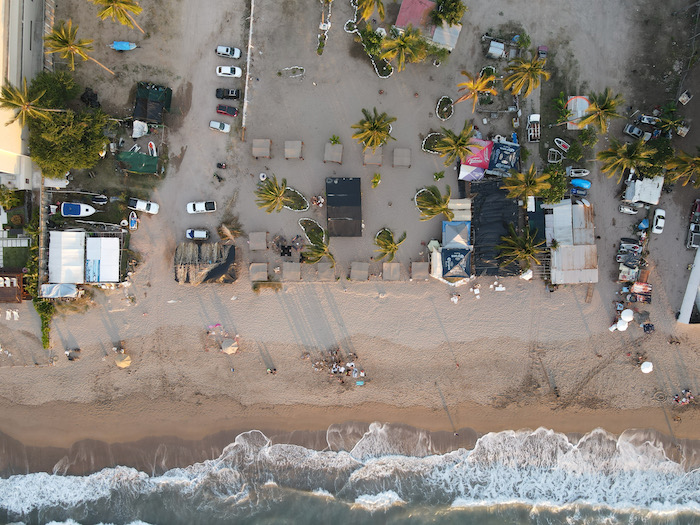 drone shot capturing the beauty of the beach from above, with pristine turquoise waters meeting the golden sand, creating a captivating coastal scene