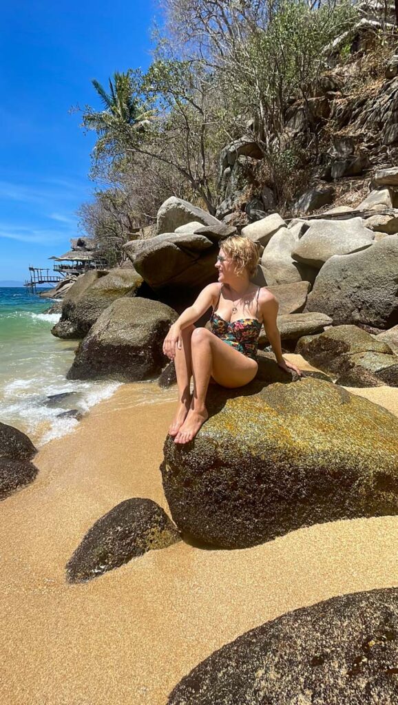 lora sitting on rocks next to Playa Colomitos