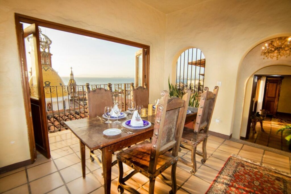 Bright and elegantly furnished room at Hotel Bellview, featuring floor-to-ceiling windows that offer a stunning view of the historic church's ornate spire, set against the vibrant cityscape of Puerto Vallarta