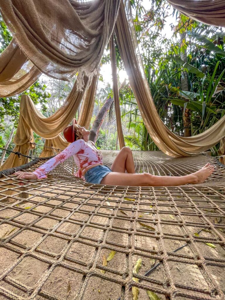 lora sitting on a net staring at the sun at majahuitas beach club