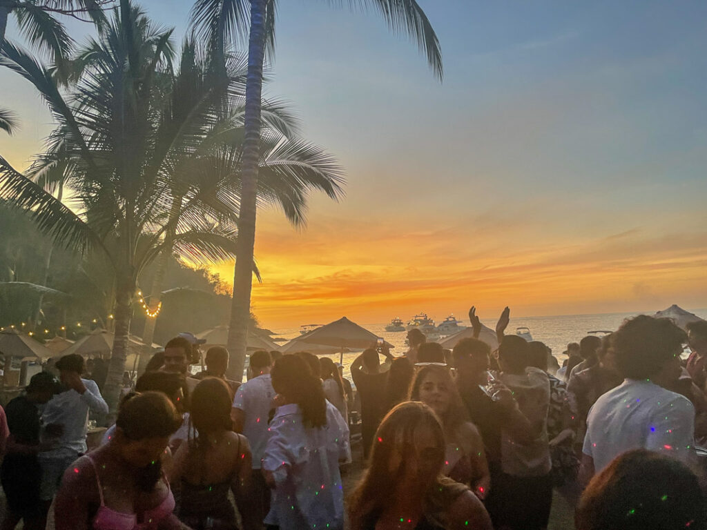 crowd of people dance as the sun sets at majahuitas beach club