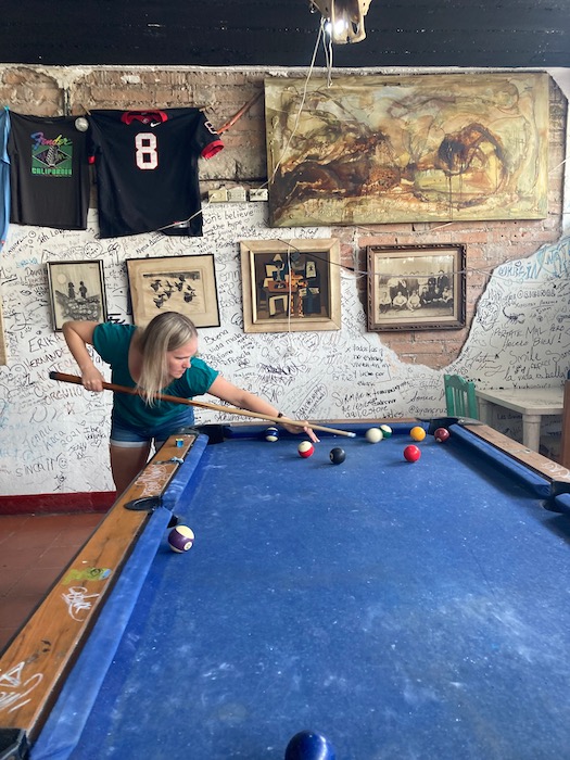 girl playing a game of pool inside a dive bar at gusto lounge