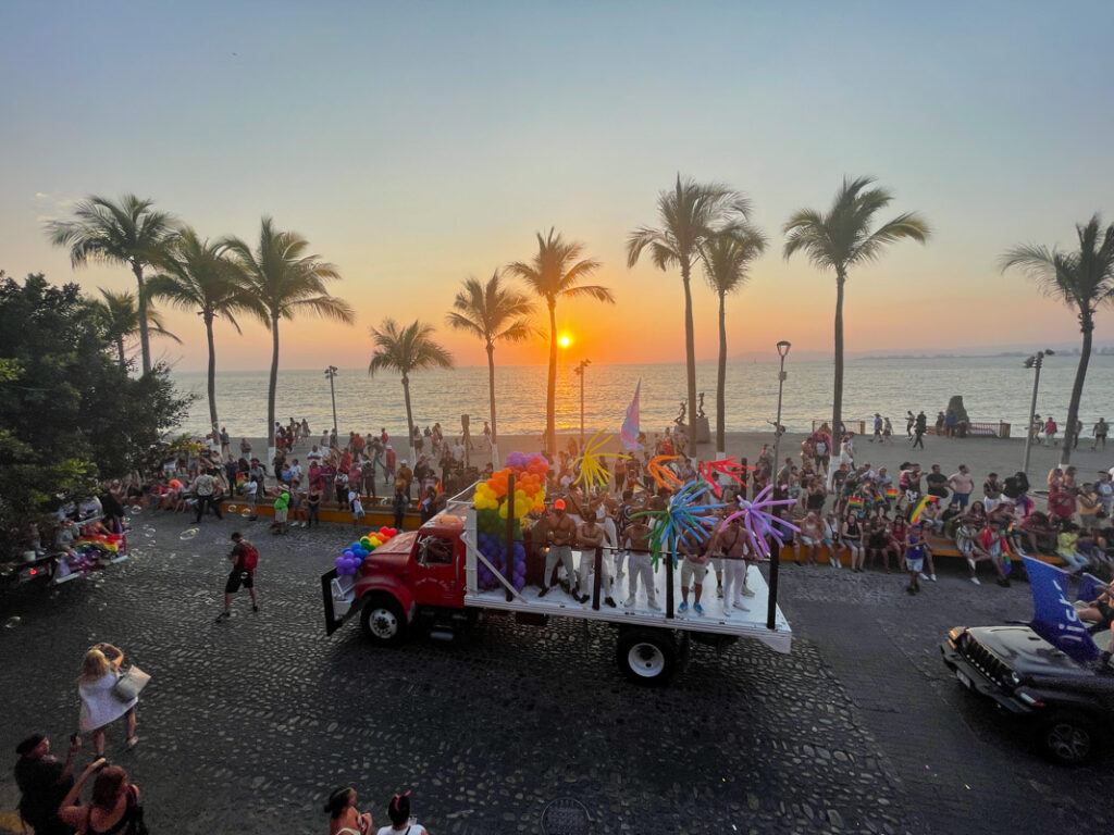 A parade of people on a street with palm trees in the background.