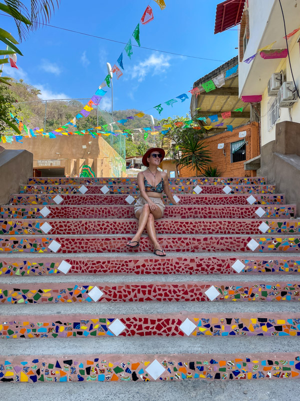 Perched gracefully on a vibrant set of stairs, Lora embraces the lively spirit of Yelapa 