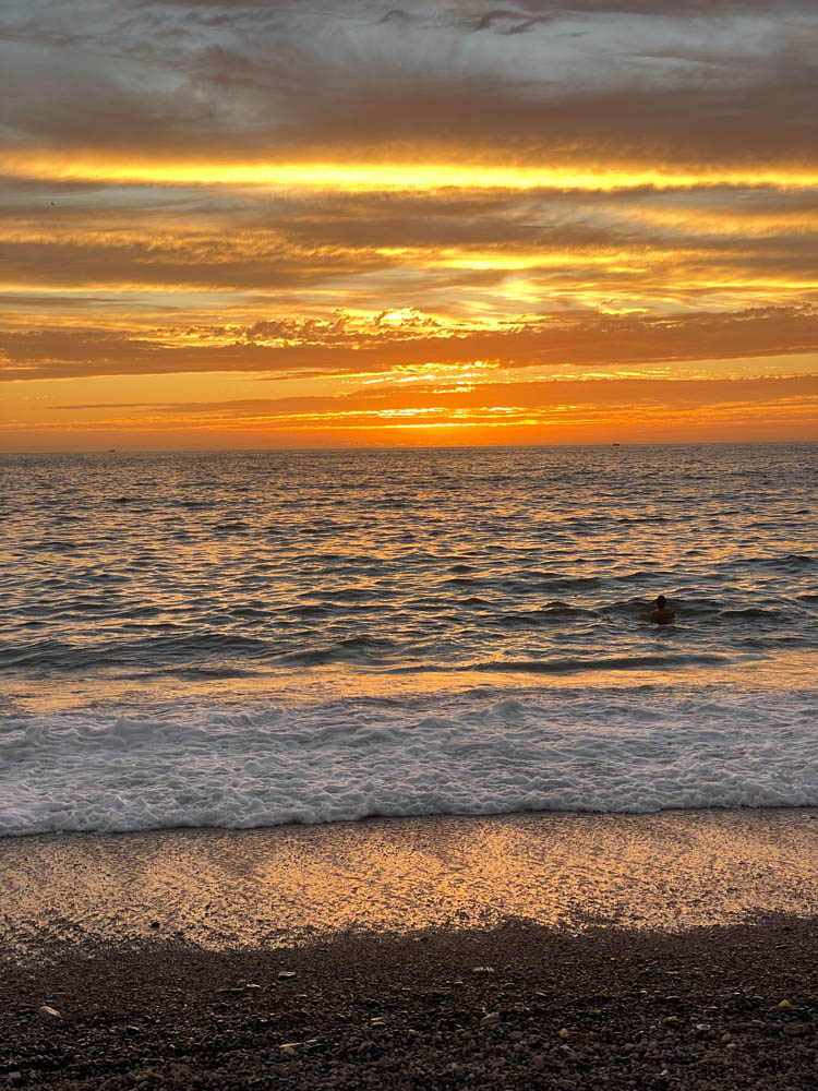 A radiant sunset painting the sky with hues of orange and pink over the tranquil waters of Puerto Vallarta's coast