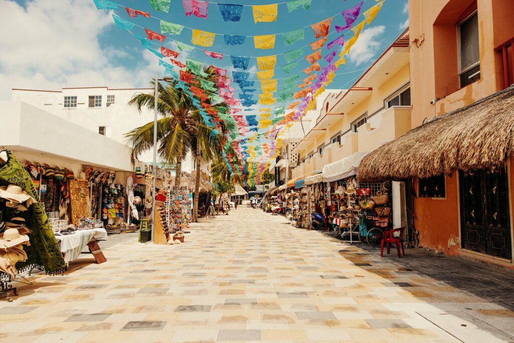 Image of a treet in downtown Playa del Carmen, Mexico, lined with vibrant shops, restaurants, and colorful facades.