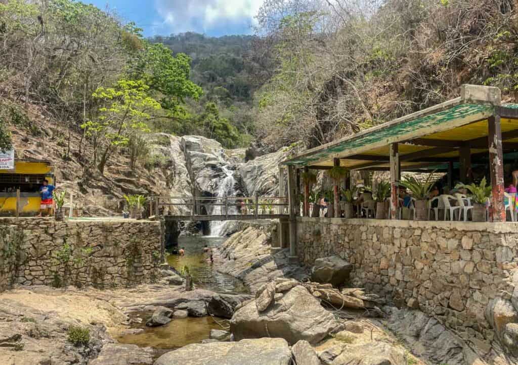 restaurant by quimixto waterfall with tourists swimming in it