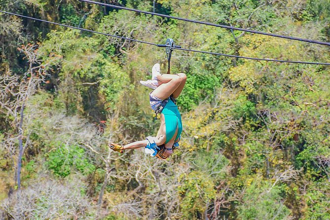 girl hanging off zipline course in jungle