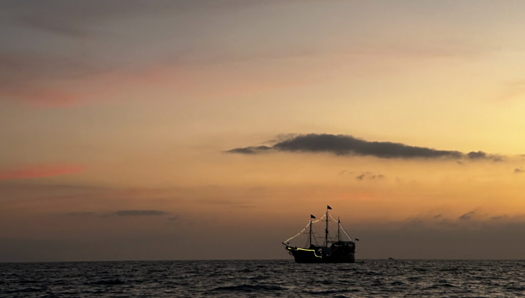 the pirate ship sailing in the ocean during sunset in puerto vallarta