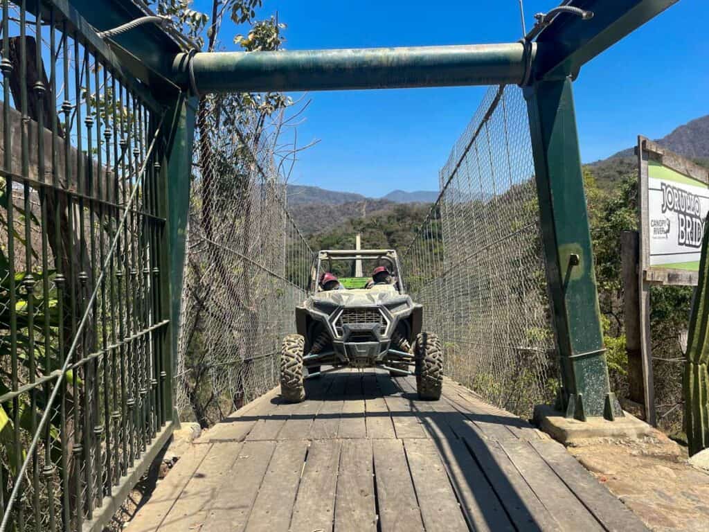 Adventurous ATV riders crossing the Jorullo Bridge, adding excitement and action to their off-road exploration at Canopy River.