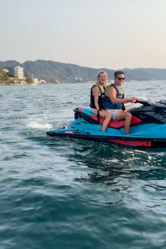 Two people riding a jet ski with majestic mountains providing a stunning backdrop.
