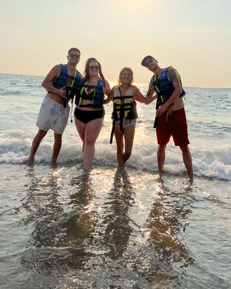 Four friends wearing life jackets in the ocean before going on jet skis