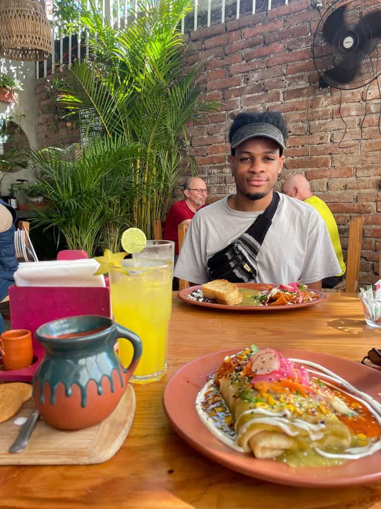 man smiling eating breakfast at macareno with colorful plate of chiliquilas in front of him