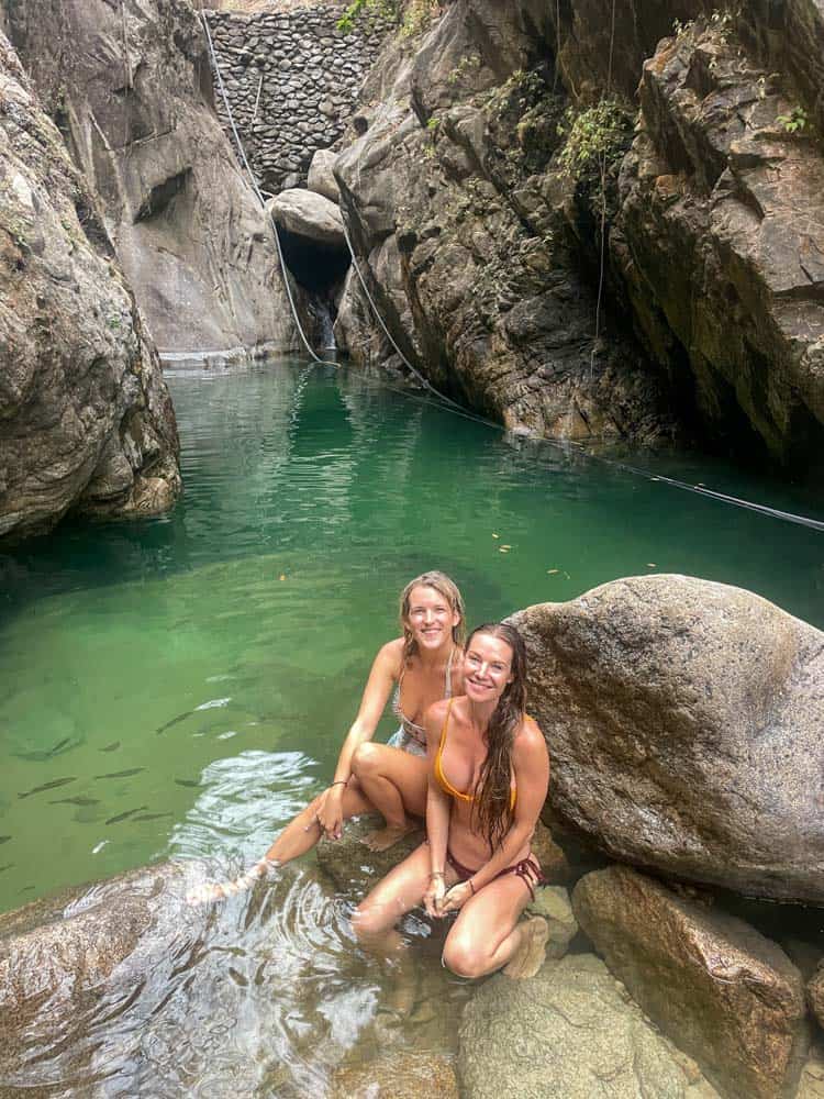 two girls on a rock in front of palo maria waterfall puerto vallarta