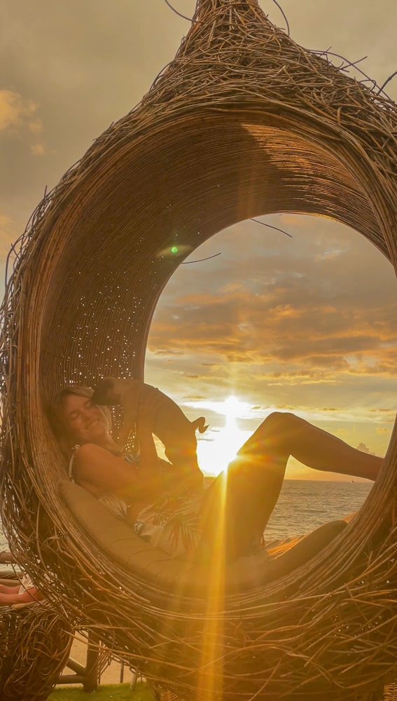 lora holding dog on a bamboo swing with the sunset light beaming in