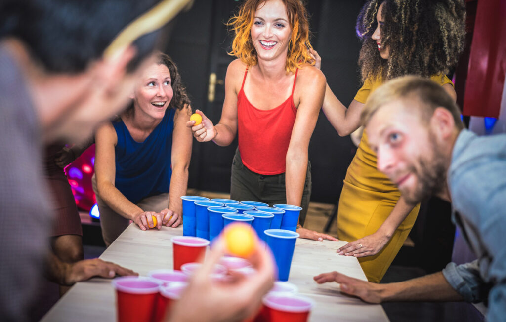 Young friends playing beer pong at youth hostel 