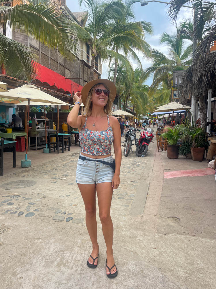 A woman in shorts and a hat posing at popular Puerto Vallarta Instagram spot.