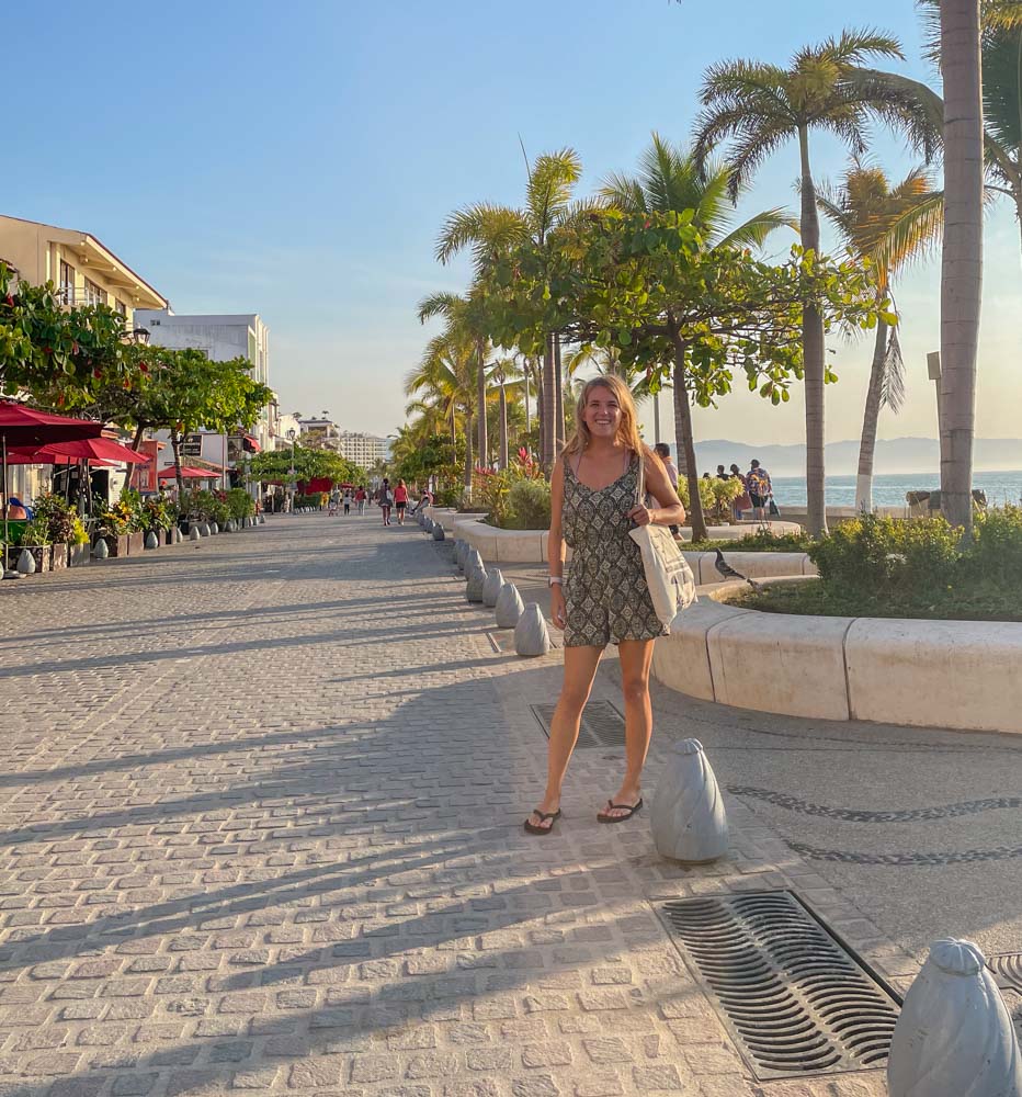 A woman posing on a Puerto Vallarta sidewalk surrounded by palm trees for Instagram.