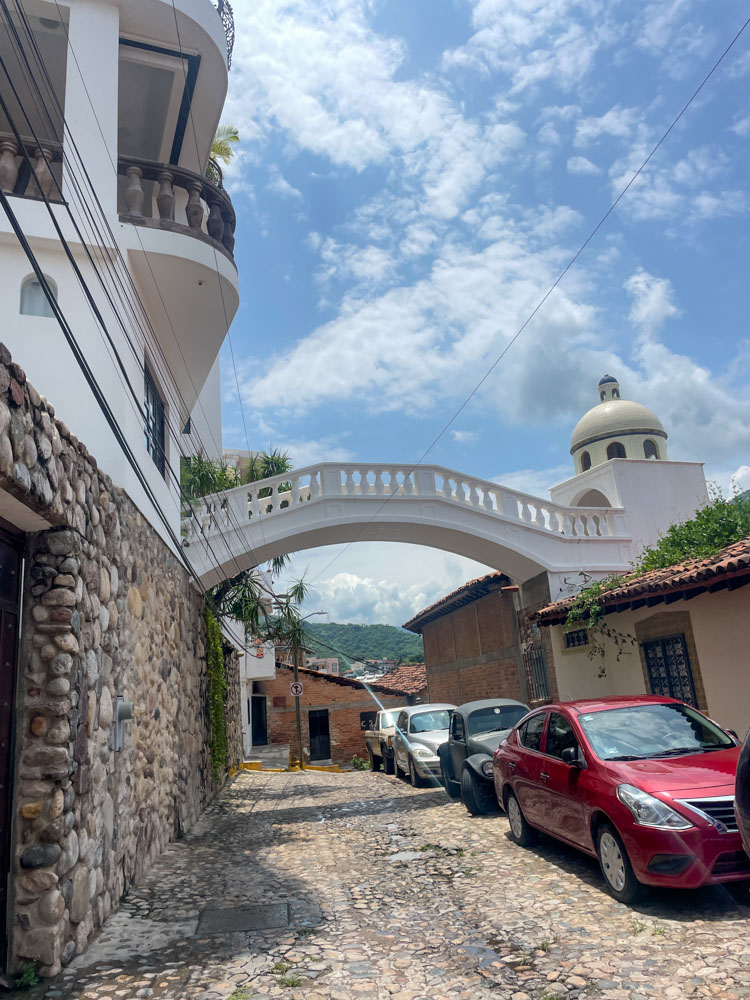 A stone building on a street in Puerto Vallarta with two parked cars.