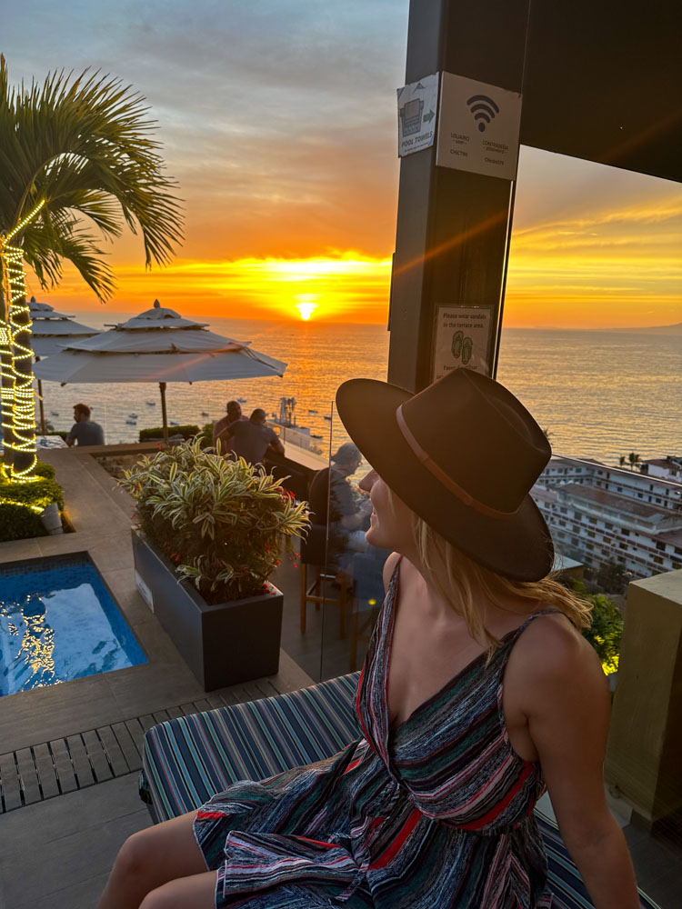 A woman wearing a hat enjoys the beautiful ocean view on a deck in Puerto Vallarta, one of the top Instagram spots.