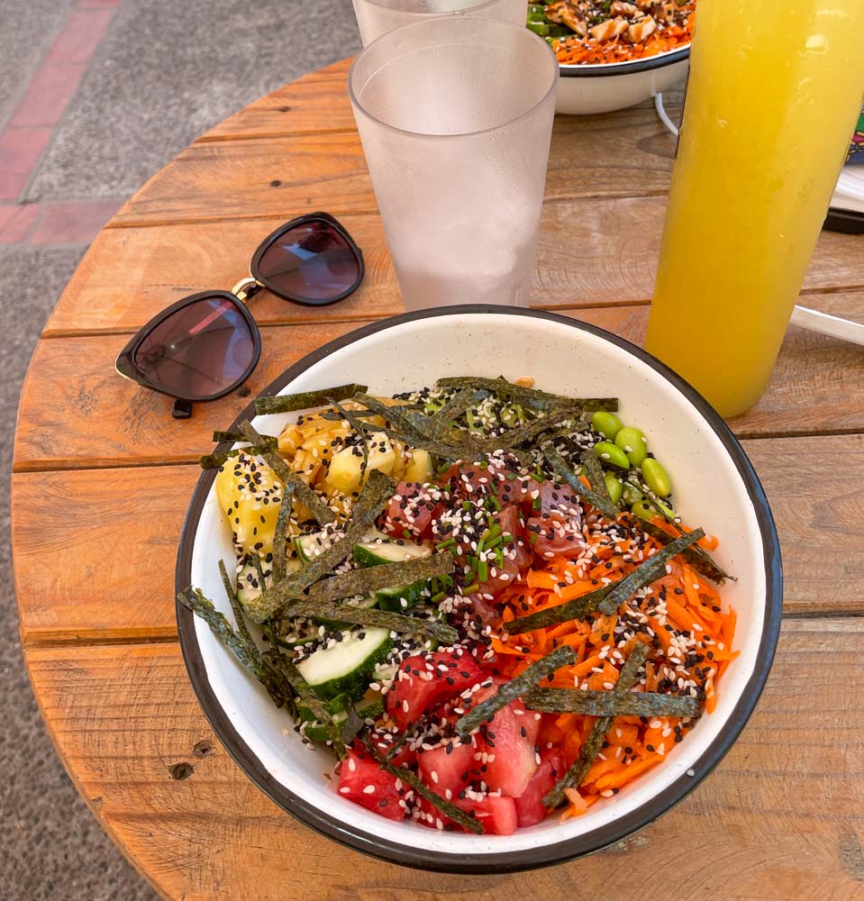 a colorful bowl of poke poke with a pair of sunglasses next to it